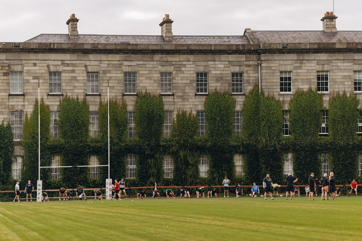 Rugby practice on a grass field beside a university building in Dublin.